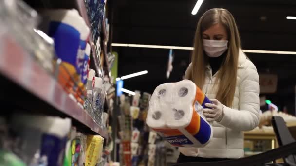 Chica en una máscara en el mercado en un fondo de papel higiénico — Vídeos de Stock