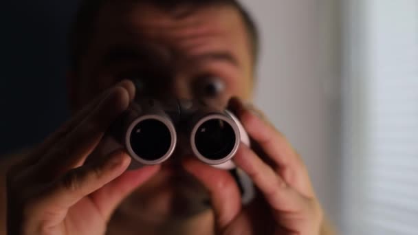 Человек шпионит за людьми, использует бинокль для наблюдения — стоковое видео