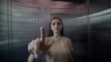 Kadın asansör çağrı düğmesine basıyor. Asansöre giriş.