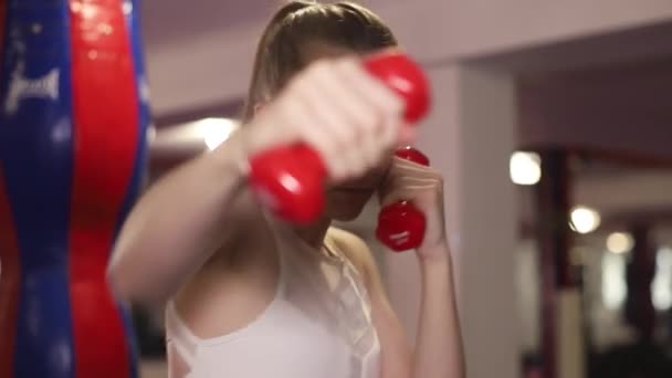 Girl boxer exercises punches with dumbbells in hand. Training at the boxing hall. — Vídeo de Stock