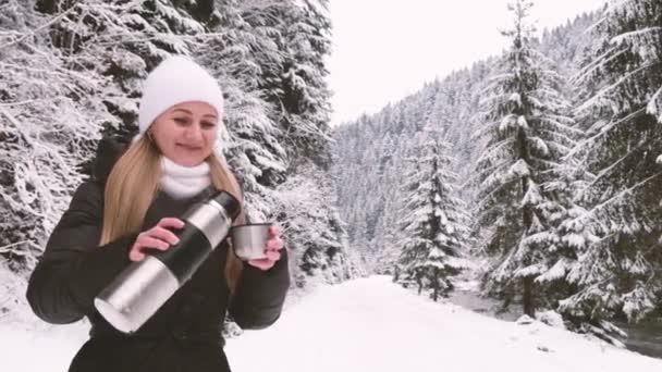 Meisje dat thee drinkt in het winterbos, een geweldige plek met een prachtig besneeuwd bos — Stockvideo