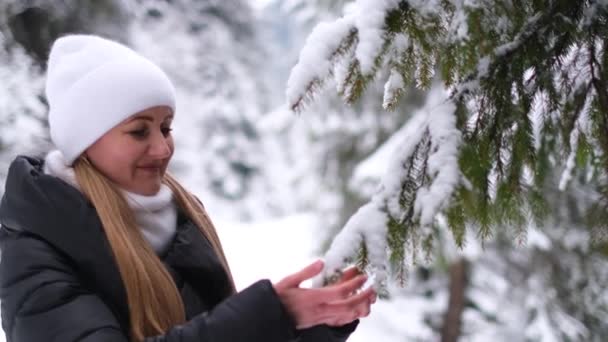 Meisje met een witte hoed in het midden van het bos kijkt naar een groene kerstboom. Sfeer voor de vakantie — Stockvideo