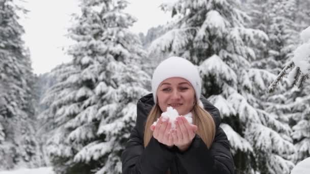 Το κορίτσι κρατά το χιόνι στα χέρια της, είναι χαρούμενη και χαμογελαστή ενώ παίζει με το χιόνι — Αρχείο Βίντεο