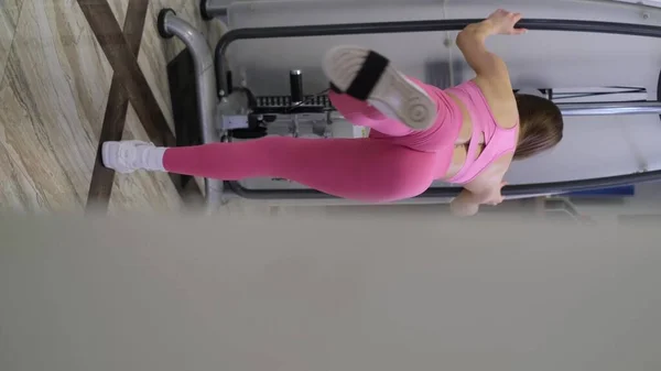 Dziewczyna na siłowni trenuje mięśnie nóg. Stylowe ciało szkoleniowe młodej kobiety — Zdjęcie stockowe