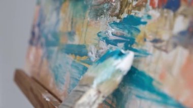Close-up motion of a brush of an artist who paints a picture with blue paints