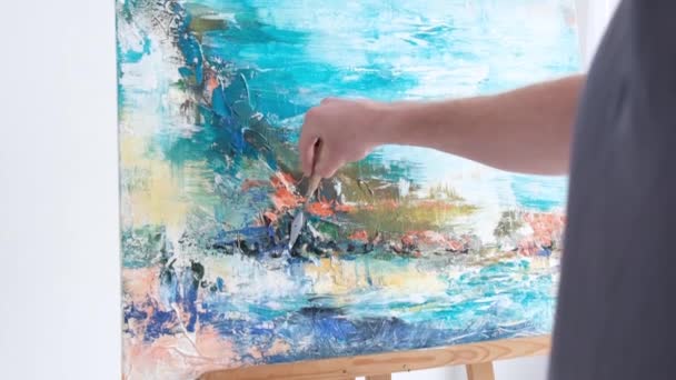 Close up of an artist painting a picture, he works in his art studio. Painting on white canvas — Vídeo de stock