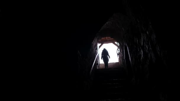 Seorang wanita berjalan melalui terowongan gelap yang panjang. Kameranya mendekat.. — Stok Video