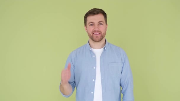 The guy shows his thumb up, he is wearing a denim shirt on an olive background. — Stockvideo