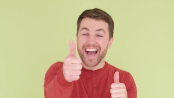 Happy man smiling, he shows thumbs up, wearing an orange sweater. Human hand gestures. — Stockvideo