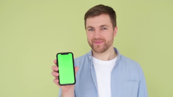 Portrait of a handsome guy holding a smartphone in his hands and smiling, looking at the camera. — Stock Video