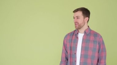 An adult man having fun on a yellow-green background in the studio, he pretends to shoot