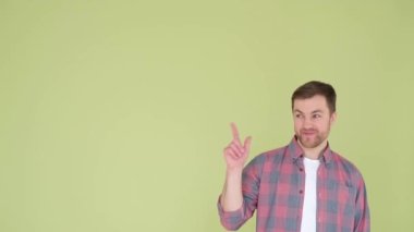 A handsome guy of European appearance in a shirt shows his finger towards the advertising space