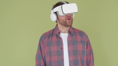 Man in 3d glasses on a yellow and green background in the studio. Young man uses vr glasses to work 
