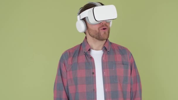 Человек в 3D очках на желтом и зеленом фоне в студии. Молодой человек использует VR очки для работы — стоковое видео