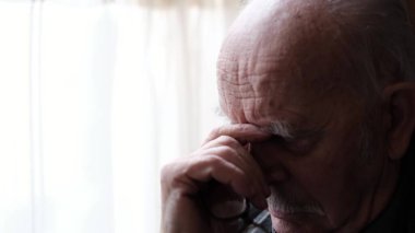 Yaşlı emekli şiddetli migren krizi geçiriyor. Yorgun ve yaşlı bir adam baş ağrısı çekiyor.