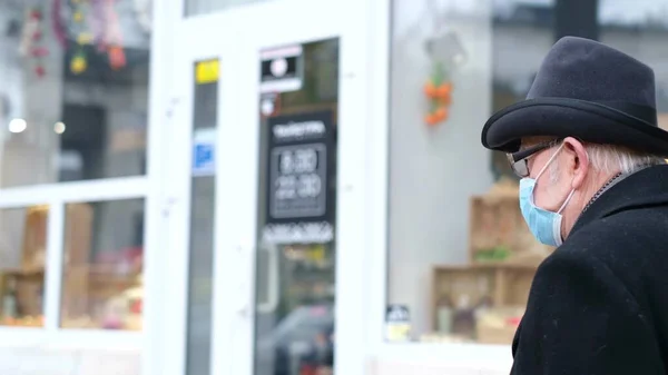 Um pensionista caminha pelas ruas de uma cidade europeia durante a quarentena. Avô em uma máscara protetora — Fotografia de Stock