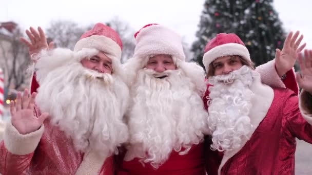 Três engraçados velhos Papai Noel barbudo boas-vindas ao Ano Novo, eles acenam suas mãos oi — Vídeo de Stock