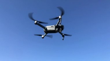 Mavi gökyüzüne karşı uçan bir dron. 4k video