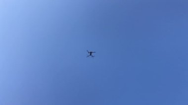 Mavi gökyüzüne karşı uçan bir dron. 4k video
