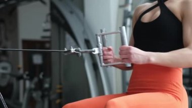 Close up of sports girl in the gym. The girl does an exercise on the back muscles in traction.
