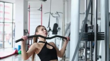 Siyah bluzlu atletik kadın spor salonunda sırt kası pompası kullanıyor.