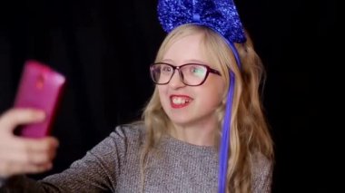 Siyah arka planda akıllı telefonu olan küçük bir kız, yakın plan.