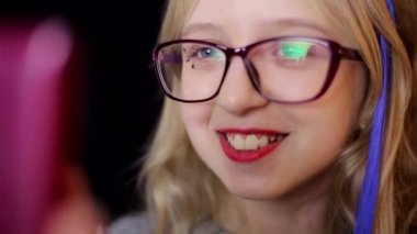 Siyah arka planda akıllı telefonu olan küçük bir kız, yakın plan.