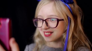 Siyah arka planda akıllı telefonu olan küçük bir kız, yakın plan.