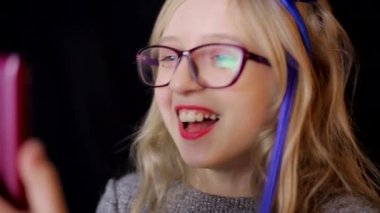 Siyah arka planda akıllı telefonu olan küçük bir kız, yakın plan.