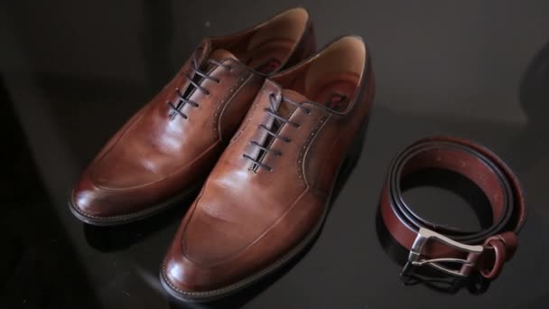 Selective focus of mens leather belt and shoe on table, brown shoes and strap — Stok video