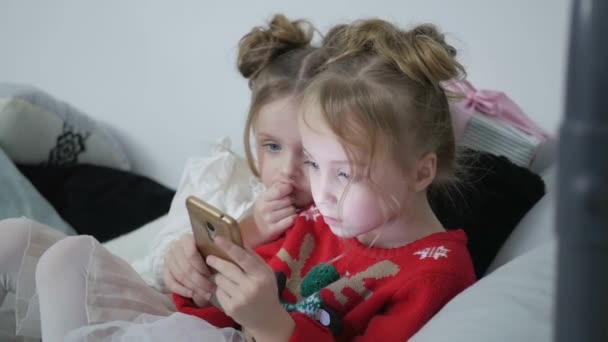 Παιδιά μιας ομάδας κοριτσιών που παίζουν στο Διαδίκτυο από ένα κινητό smartphone στον καναπέ, ευτυχισμένη οικογένεια — Αρχείο Βίντεο