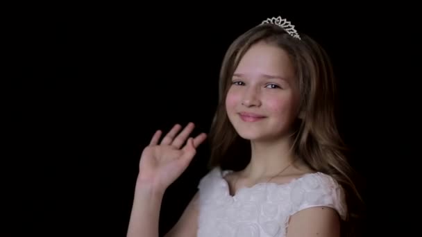 Cute beautiful Carnival kid is having fun isolated on a black background. Cute little girl with a crown on her head, expressing interest in the camera — Wideo stockowe