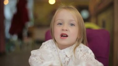 Complete the shot of a beautiful blond Caucasian little girl looking at the camera with a charming smile. Happy concept of childhood