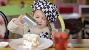 Doğum günü pastası ısırma güzel mutlu küçük kız. Kameraya bakarak.