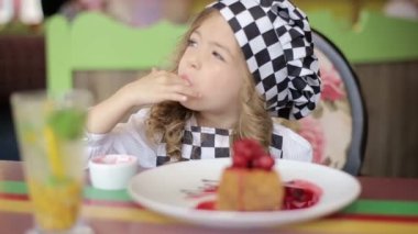 Doğum günü pastası ısırma güzel mutlu küçük kız. Kameraya bakarak.