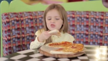 Küçük şirin Avrupalı bebek pizza yiyor. Pizzanın üstünde pizza yiyen aç bir çocuk..