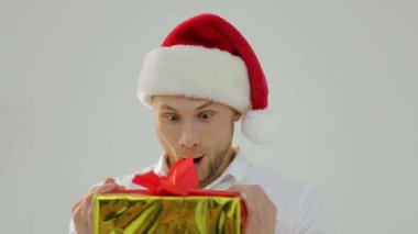 Christmas sales concept. Happy Christmas man holding small shopping cart with christmas gift, isolated. Copy space. New Years Holiday. Winter sales. Smiling man in Santa hat with shopping basket