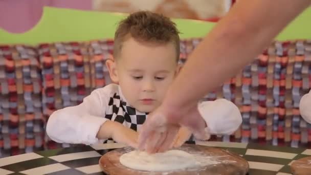 Маленький мальчик в костюме повара делает тесто для пиццы. Ребенок готовит ужин в костюме шеф-повара — стоковое видео