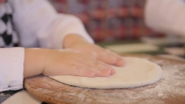 Little girl sprinkling flour over the kitchen table, helping her mother to bake a pizza dough — Wideo stockowe