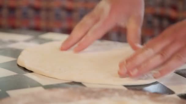 Маленькая девочка поливает мукой кухонный стол, помогая матери печь тесто для пиццы — стоковое видео