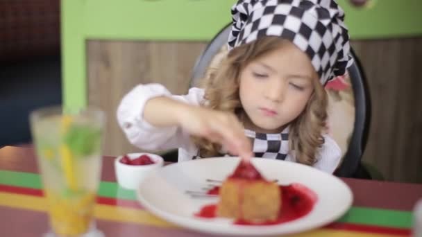 Cute little girl eating cake. pretty little girl with cake and strawberries. child eating dessert. girl eating with spoon by the table — Wideo stockowe