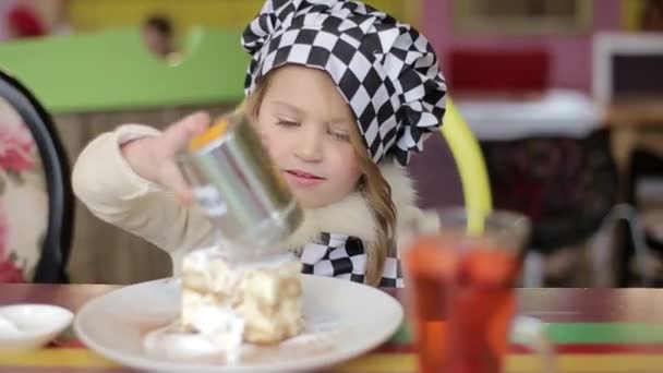 Прекрасная счастливая маленькая девочка, кусающая торт. Смотреть в камеру . — стоковое видео