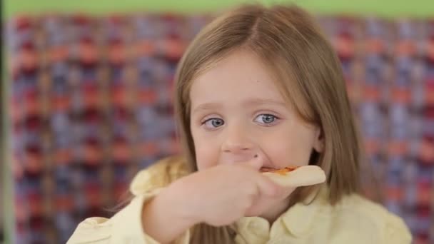 Nice little European baby eating pizza. A hungry child who takes a bite from pizza on a pizza. — Wideo stockowe