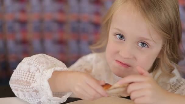 Nice little European baby eating pizza. A hungry child who takes a bite from pizza on a pizza. — Stockvideo