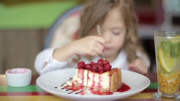Słodka dziewczynka jedząca ciasto. Ładna dziewczynka z ciastem i truskawkami. dziecko je deser. dziewczyna jedzenie z łyżeczką przy stole — Wideo stockowe