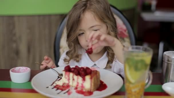 Śmieszne dziewczynki, chowając się za biały stół i patrząc na smaczne ciasto — Wideo stockowe
