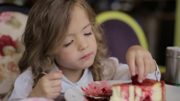 Cute little girl eating cake. pretty little girl with cake and strawberries. child eating dessert. girl eating with spoon by the table — Wideo stockowe