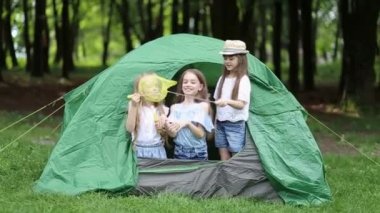 Parktaki çadırda yatan gülümseyen çocuklar.