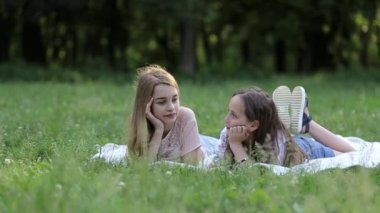 Bir grup mutlu çocuk bir bahar parkında yeşil çimlerde uzanıyorlar, bir çadır kampında.