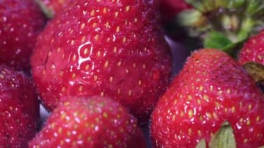 Olgun kırmızı çileklerin kırmızı arkaplanı. Yaklaş, üstten bak. Çilekleri bir çemberde döndürür